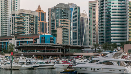 Wall Mural - Dubai Marina towers and yachts reflected in water of canal in Dubai day to night timelapse