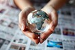 Close view of hands holding a globe over financial newspapers, symbolizing global economic challenges