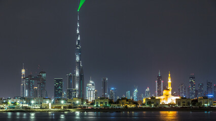 Wall Mural - Modern Dubai city skyline timelapse at night with illuminated skyscrapers over water surface