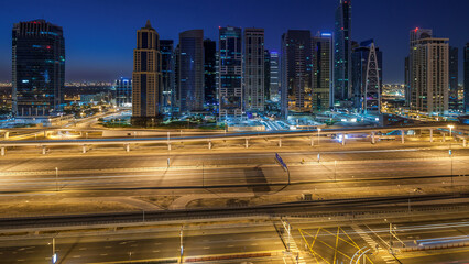 Wall Mural - Aerial view of Jumeirah lakes towers skyscrapers night to day timelapse with traffic on sheikh zayed road.