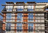 Fototapeta Na sufit - The facade of a house under construction with scaffolding