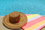 Fototapeta Na sufit - Straw beach hat and towel on the edge of the pool