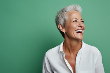 Wall Mural - Cheerful senior woman. Side view of beautiful mature woman smiling and looking away while standing against green background