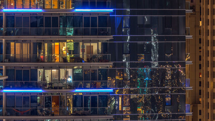 Wall Mural - Glowing windows in multistory modern glass and metal residential building light up at night timelapse.