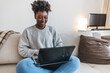 Black woman, laptop and remote work in living room for elearning, subscription info and social media. Happy freelancer typing on computer to search internet website, online shopping and reading blog