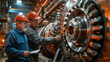 Two industrial workers with hard hats closely examine the components of a large metallic turbine in a manufacturing plant.