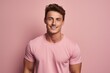 © Loli - Handsome young man in pink t-shirt smiling at camera while standing against pink background