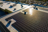 Fototapeta Mapy - Production of sustainable energy. Aerial view of solar power plant with blue photovoltaic panels mounted on industrial building roof for producing green ecological electricity