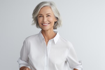 Wall Mural - Portrait of smiling mature businesswoman standing with arms crossed against grey background