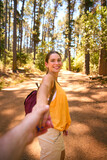 Fototapeta  - POV Shot Of Loving Couple Wearing Backpacks Holding Hands Hiking Along Trail Through Countryside