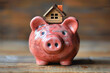 A piggy bank with a miniature house. saving money, selling real estate, mortgage investments to buy a house, preparing for a new home concept.
