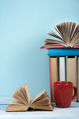 Wall Mural - Open book, hardback books on wooden table and blue background. Back to school. Copy space for text.
