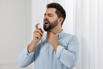 Sticker - Young man using throat spray at home