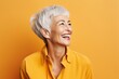 Cheerful senior woman. Portrait of cheerful mature woman looking away and smiling while standing against yellow background