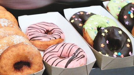 Poster - A tray of donuts with pink frosting and chocolate sprinkles. The donuts are arranged in a row and are displayed in a box