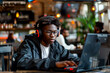 Young African American gamer immersed in laptop game at cafe with empty space for text or design. Ideal for adding creative content.