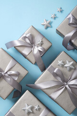 Wall Mural - Set of monochrome gray gift boxes with gray ribbons and silver stars on light blue background. Vertical, copyspace