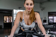 © Marino Bocelli - young cute woman in tight sports suit training on exercise bike in gym