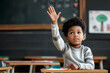 portrait of 7-year-old black boy sitting in modern classroom near blackboard,taking an active part in learning,raising his hand,concept of educational materials,development and upbringing of children