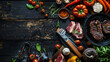 A festive summer BBQ flat lay with grilling tools various meats vegetables and spices on a dark wooden plank background.