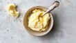 Creamy butter in a bowl with a spoon on a textured background. Healthy fresh farm dairy product