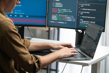 IT developer working online software development on pc monitors at modern home office on coding application screens, creating updated latest program firmware information version concept. Gusher.