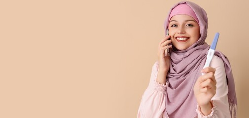 Wall Mural - Happy Muslim woman with pregnancy test talking by mobile phone on beige background with space for text