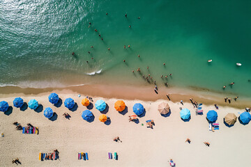 Wall Mural - Aerial view of sandy beach with colorful umbrellas, swimming people in sea bay with transparent blue water in summer. Top view