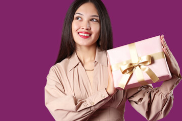 Sticker - Beautiful young Asian woman with gift box on purple background