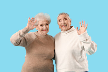 Poster - Senior female friends waving hands on blue background