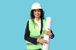 © Pixel-Shot - Beautiful young happy African-American female engineer with blueprint on blue background