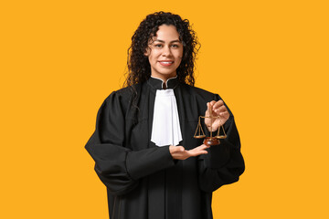 Poster - Beautiful young happy African-American female judge with scales of justice on yellow background