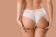 © Pixel-Shot - Young woman in white lace panties on brown background, back view