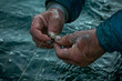 a pair of hands threading a fishing line through a hook