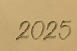 Drawing sun and 2025 on the sandy beach of the coastline as a symbol of the beach season
