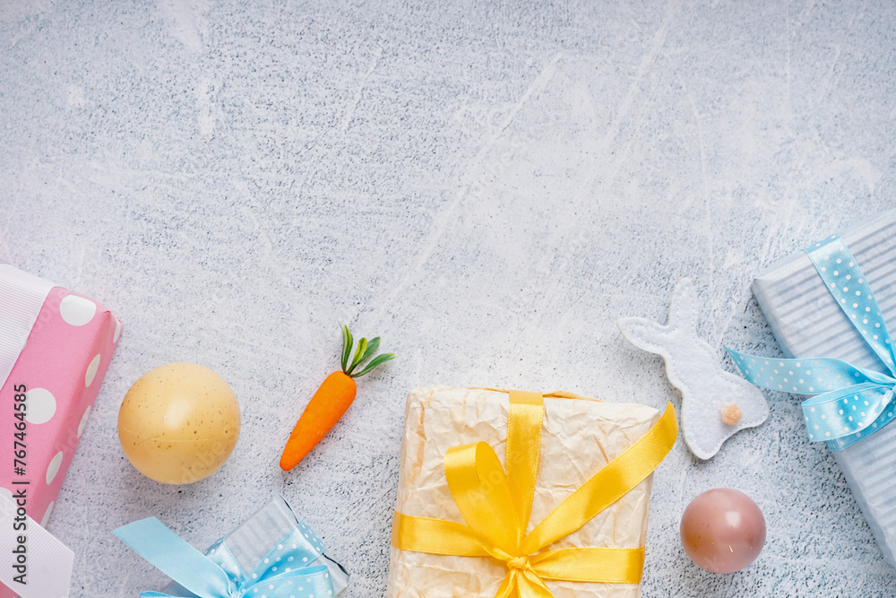 Painted Easter eggs with gift boxes and toy bunny on white grunge background