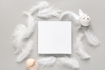 Wall Mural - Feathers, decorated Easter eggs and empty paper sheet on grey background