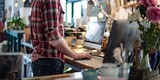Fototapeta  - Man wearing red plaid shirt and jeans working behind counter of small business