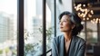 © Kristian - mature optimistic asian businesswoman woman female executive CEO in corporate modern office thinking contemplating and looking out window skyscraper cityscape daytime with room for text