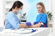 © New Africa - Laboratory testing. Doctor taking blood sample from patient at white table in hospital