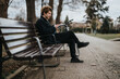© qunica.com - A modern entrepreneur enjoys a restful moment on a park bench with their bicycle beside them, using a smart phone.