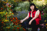 Fototapeta  - A woman poses in her flower garden.