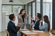 © crizzystudio - Smiling Asian businessman raising his hands Clapping happily at the table in the office Group of successful Asian business teams discuss cooperation Presentation and analysis of successful reports.