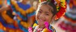 A young girl smiles as she performs in a colorful traditional Mexican dance costume with others in motion around her.