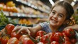 A young girl with a big smile reaches for red tomatoes at a grocery store