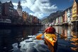 tourist athlete floats on a yellow kayak boat on the river against the background of houses on the shore in the fjords of norway
