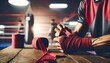 A close-up of a boxer's hands being wrapped in red boxing wraps in preparation for a training session.