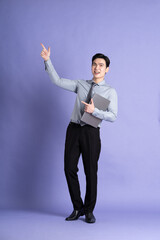 Portrait of Asian male businessman standing and posing on purple background