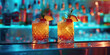 Two drinks on a bar counter with a blue background. The drinks are garnished with fruit and are in martini glasses
