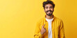 An overjoyed young man with a beard pointing at himself, radiating happiness and success against a yellow background.